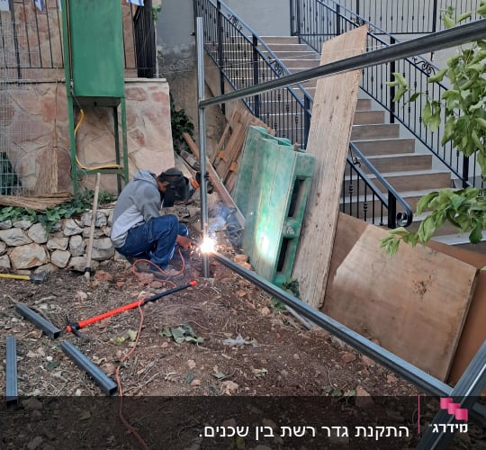 אדם מרתך מסגרת מתכת ליד מדרגות